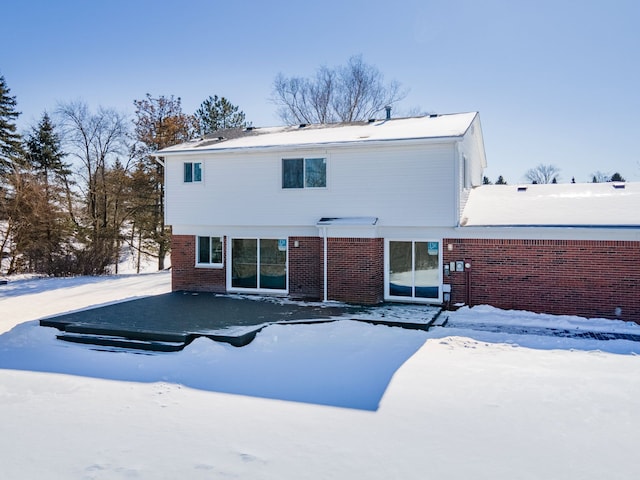 snow covered house featuring brick siding