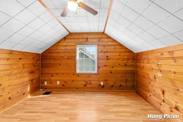 bonus room featuring vaulted ceiling, wood walls, ceiling fan, and light wood-type flooring