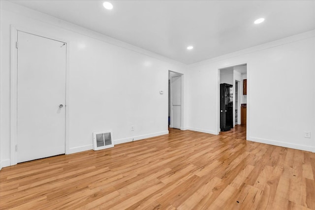 spare room featuring ornamental molding and light hardwood / wood-style flooring