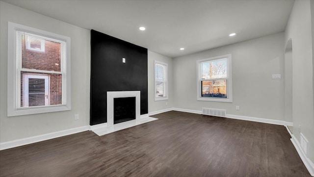 unfurnished living room featuring a large fireplace and dark hardwood / wood-style floors