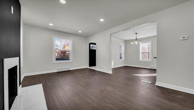 unfurnished living room with dark wood-type flooring and an inviting chandelier