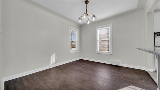 unfurnished dining area with dark hardwood / wood-style floors and a chandelier