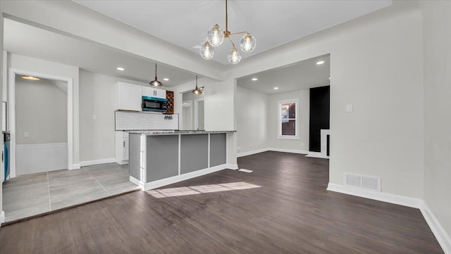 interior space featuring white cabinetry, wood-type flooring, pendant lighting, and a notable chandelier