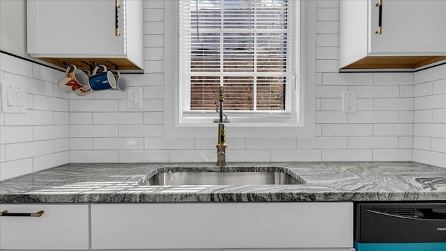 kitchen with white cabinetry, dishwashing machine, sink, and backsplash