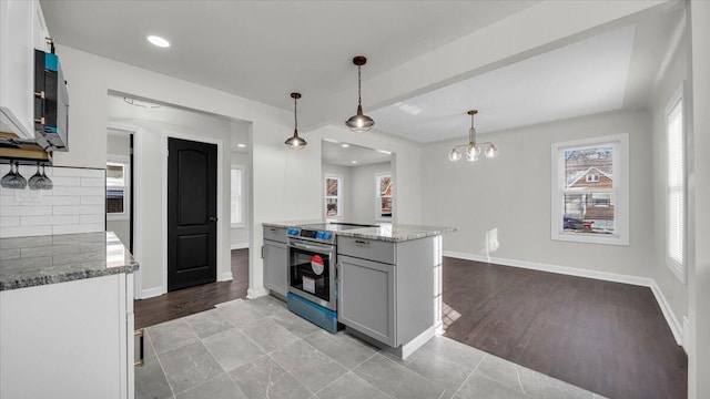 kitchen with light stone counters, stainless steel electric range oven, hanging light fixtures, and white cabinets