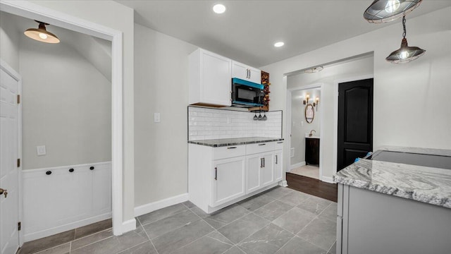 kitchen featuring white cabinetry, pendant lighting, light stone countertops, and decorative backsplash