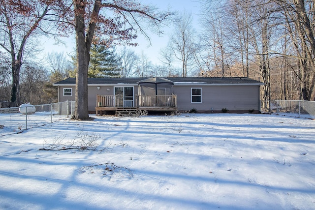 snow covered rear of property with a deck