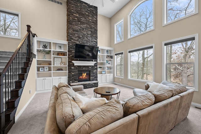 living room with light carpet, a fireplace, stairs, and baseboards