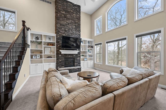 living room featuring light carpet, a wealth of natural light, and a stone fireplace