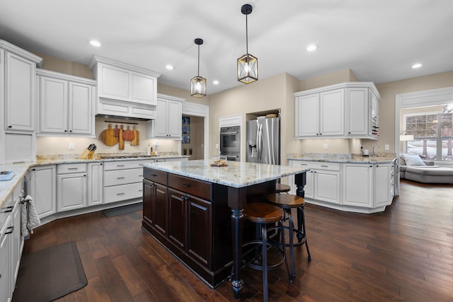 kitchen with stainless steel appliances, a center island, decorative light fixtures, and white cabinetry