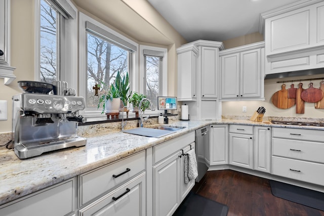 kitchen featuring light stone counters, dark wood finished floors, appliances with stainless steel finishes, white cabinetry, and a sink