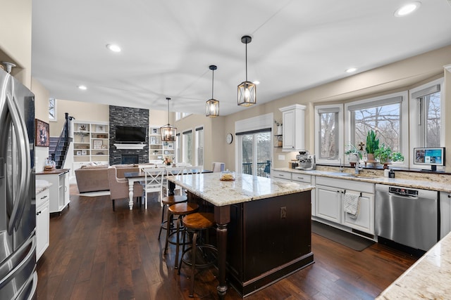 kitchen featuring a center island, pendant lighting, appliances with stainless steel finishes, white cabinetry, and a sink