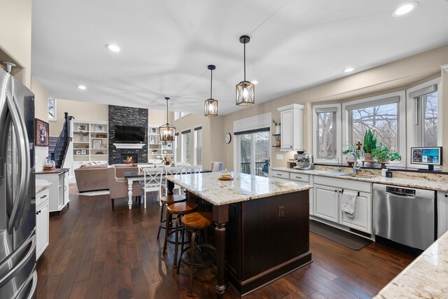 kitchen with hanging light fixtures, white cabinetry, a kitchen island, and appliances with stainless steel finishes