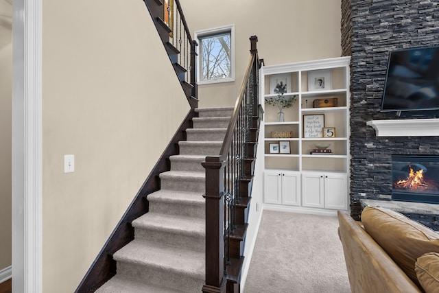 stairs featuring carpet floors and a fireplace