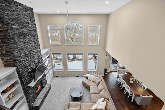 living room featuring plenty of natural light, a fireplace, and a towering ceiling