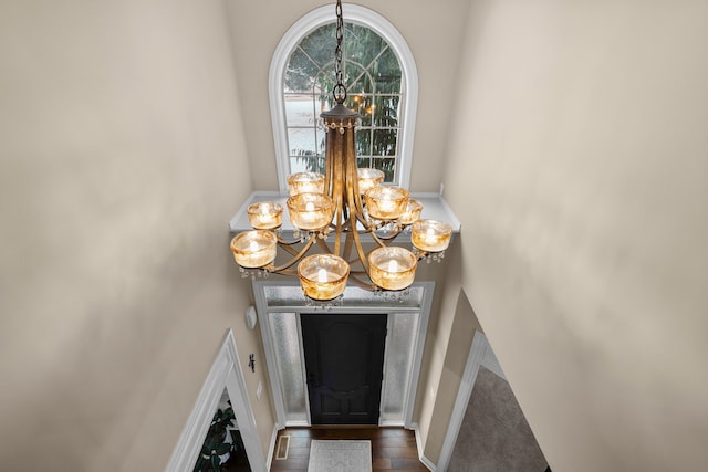 foyer with dark wood-type flooring, a notable chandelier, and baseboards