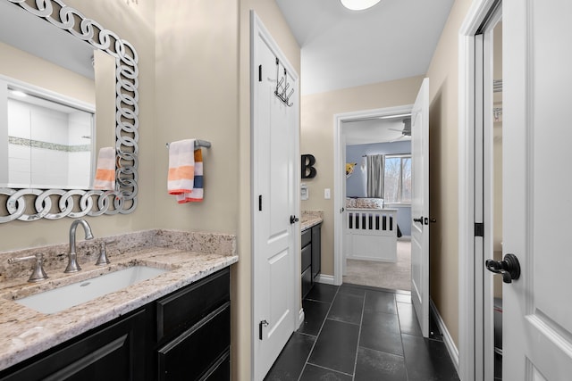 ensuite bathroom featuring tile patterned flooring, vanity, baseboards, a tile shower, and ensuite bath