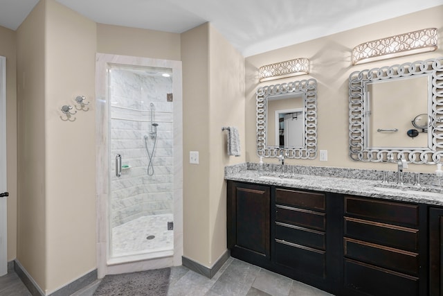 bathroom featuring double vanity, a stall shower, baseboards, and a sink