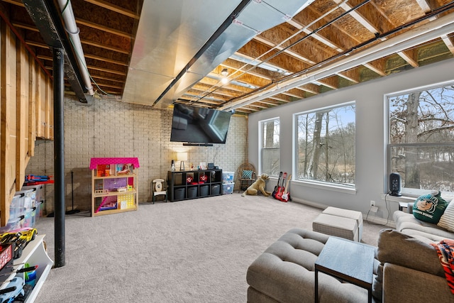 below grade area with brick wall, plenty of natural light, carpet flooring, and baseboards