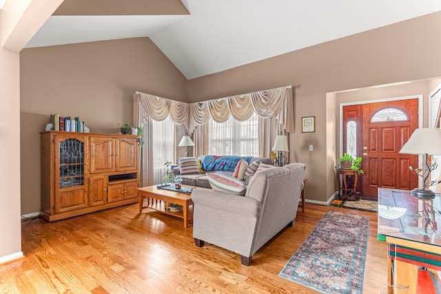 living room with high vaulted ceiling and light hardwood / wood-style flooring