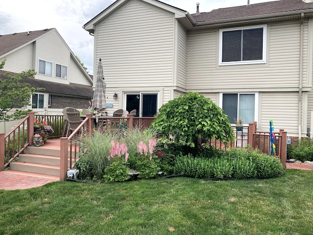 back of house featuring a lawn and a deck