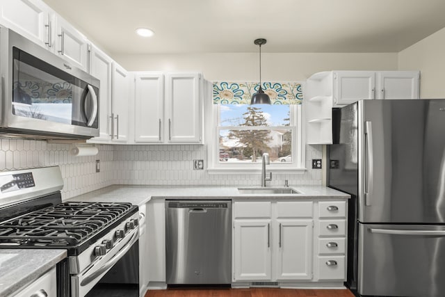 kitchen featuring white cabinetry, sink, decorative light fixtures, and stainless steel appliances