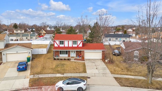 view of front of home featuring driveway, fence, a residential view, a front yard, and an attached garage