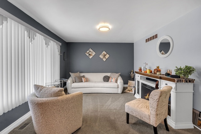 carpeted living room with visible vents, a warm lit fireplace, and baseboards