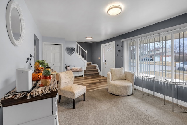 carpeted living area with stairway and baseboards