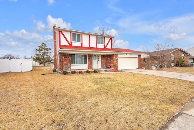 tudor-style house with fence, concrete driveway, a front yard, a garage, and brick siding