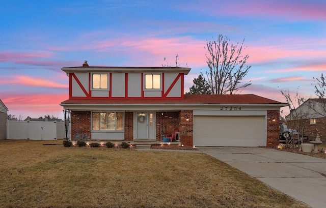 tudor-style house with a front lawn, brick siding, and an attached garage