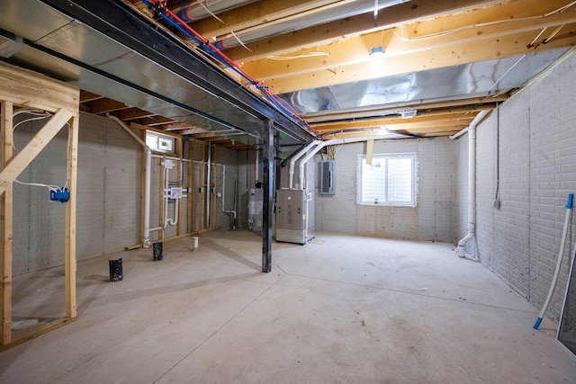 basement with heating unit, electric panel, water heater, and brick wall