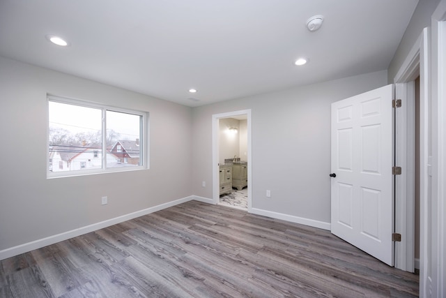 unfurnished bedroom with wood-type flooring and connected bathroom