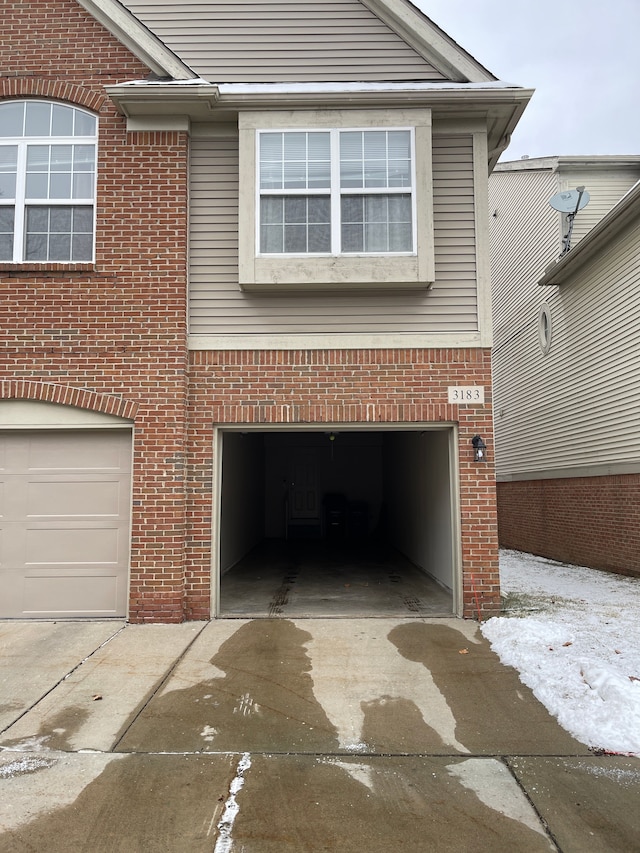 exterior space with a garage, concrete driveway, and brick siding