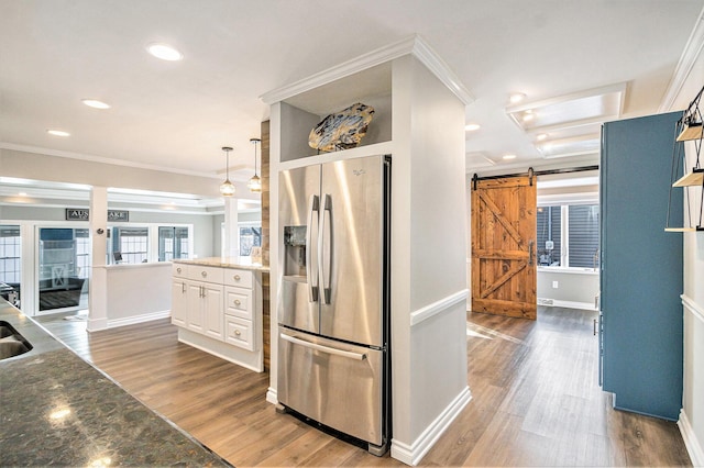 kitchen with dark hardwood / wood-style floors, white cabinets, stainless steel fridge, ornamental molding, and a barn door