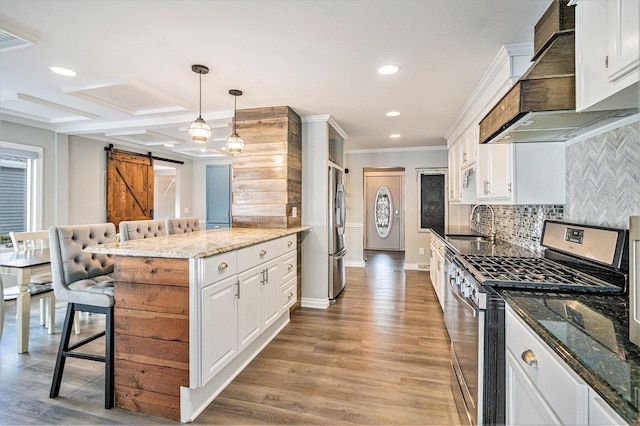 kitchen with premium range hood, white cabinetry, hanging light fixtures, stainless steel appliances, and a barn door