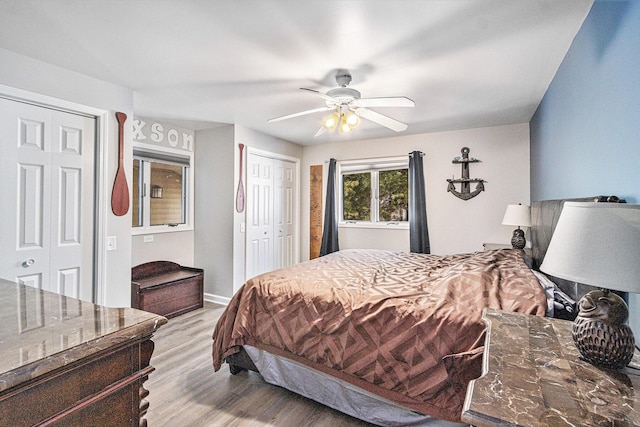 bedroom featuring multiple closets, ceiling fan, and light hardwood / wood-style flooring