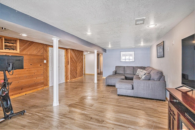 living room featuring hardwood / wood-style flooring, a textured ceiling, and wooden walls