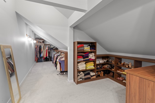 walk in closet with light colored carpet and lofted ceiling