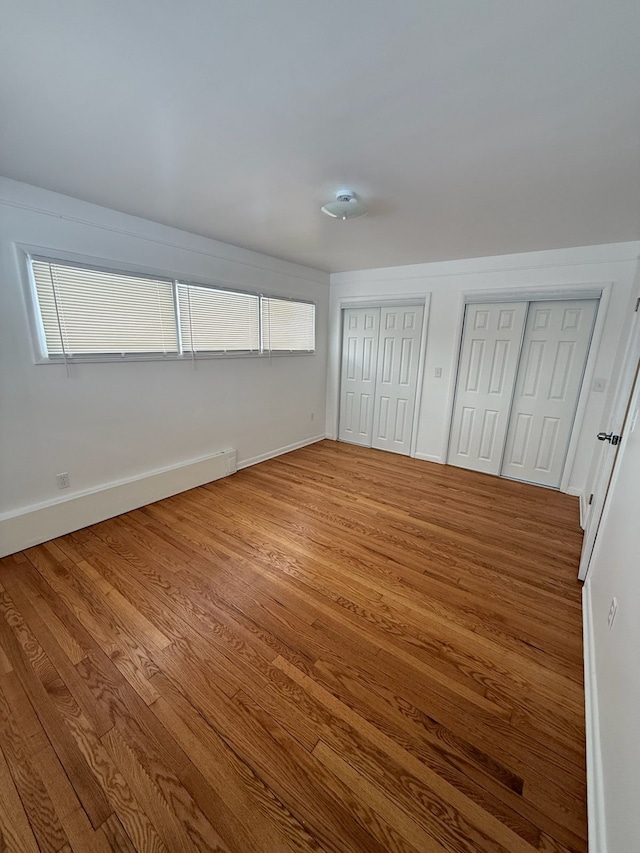 unfurnished bedroom featuring hardwood / wood-style flooring and two closets