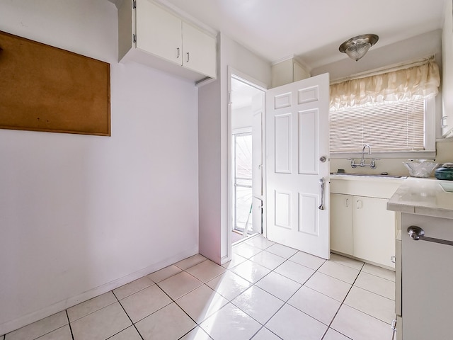 kitchen featuring light tile patterned floors, sink, and white cabinets