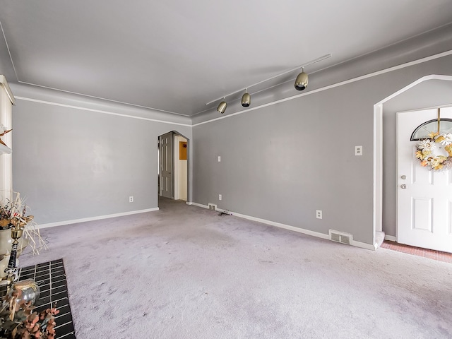 unfurnished living room featuring crown molding, track lighting, and carpet flooring