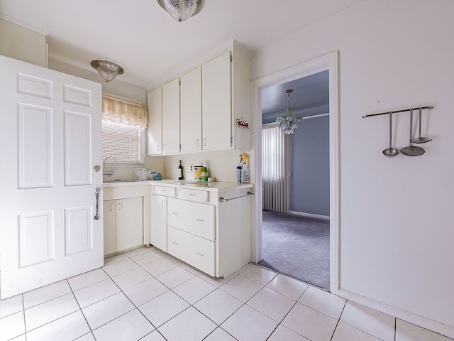 kitchen featuring white cabinetry, sink, light colored carpet, and a chandelier