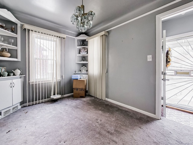 interior space with ornamental molding, a notable chandelier, and dark carpet