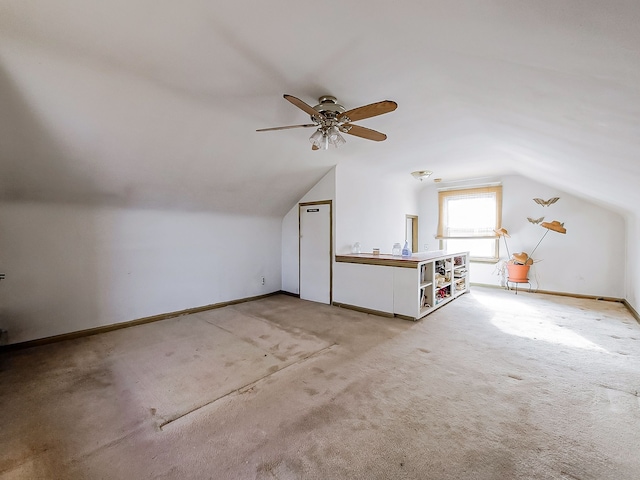 additional living space with vaulted ceiling, light colored carpet, and ceiling fan