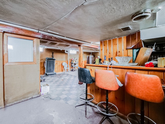 bar with a textured ceiling and wood walls