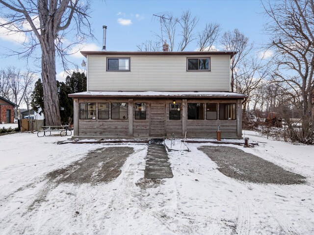 1397 N Channel Dr, Harsens Island, MI 48028 - snow covered rear of property with a chimney and a sunroom