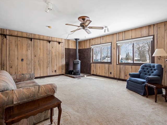 1397 N Channel Dr, Harsens Island, MI 48028 - living area with a wood stove, a ceiling fan, wooden walls, light carpet, and baseboards