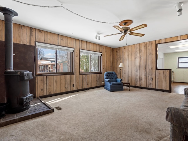 1397 N Channel Dr, Harsens Island, MI 48028 - living area with a wood stove, wood walls, ceiling fan, light colored carpet, and baseboards