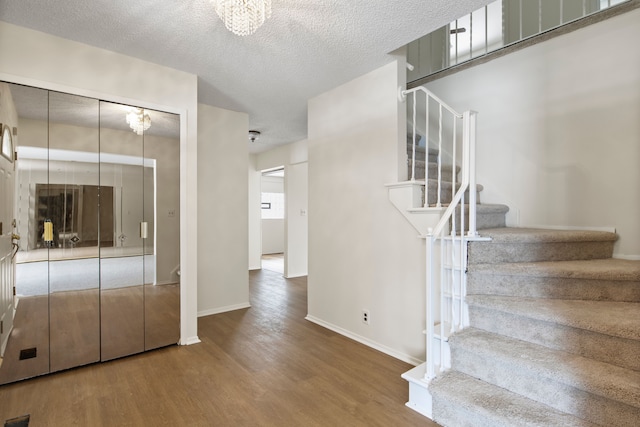 stairway featuring an inviting chandelier, hardwood / wood-style floors, and a textured ceiling